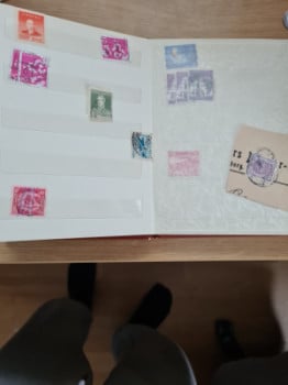 Gammal frimärksbok med 70-80 frimärken i.