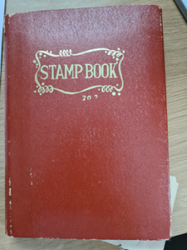 Gammal frimärksbok med 70-80 frimärken i.